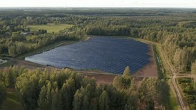Solar thermal collectors. Solar panels farm field of green renewable energy. in the middle of a forest. Aerial drone panoramic video. Strong sun reflection off of cell panels. 4k footage