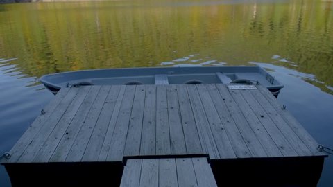 Dolly shot of a wooden landing stage with a anchored boat on the local reservoir.