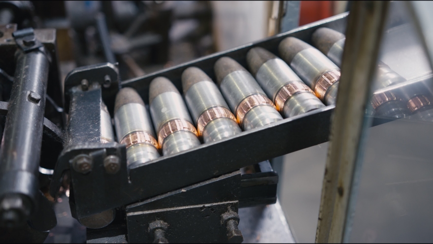 large grey bullets transported along modern machine tool by automatic production line in workshop extreme close view