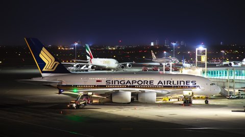 NEW YORK, NY - 2019: Singapore Airlines Airbus A380 Commercial Jet Airliner Parked at JFK John F Kennedy International Airport Terminal Gate at Night Timelapse with Moving Lights from Aviation Traffic