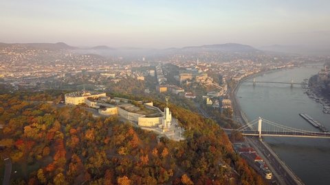 Budapest, Hungary - 4K aerial view of Autumn Morning at golden hour with Statue of Liberty on Gellert Hill, Elisabeth Bridge and Buda Castle and skyline of Budapest at sunrise.