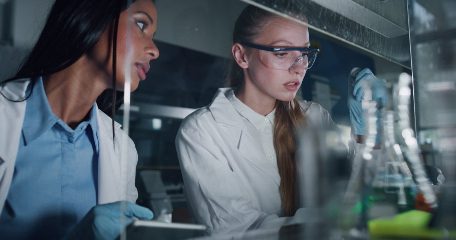Portrait of two female scientists are analyzing with a pipette a liquid to extract the DNA and molecules in the test tubes in laboratory.  | Shutterstock HD Video #1039894493
