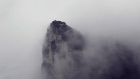 View of the massive vertical stone pillar of Tianmen mountains engulfed in low morning clouds, Zhangjiajie National park, Hunan Province, China

