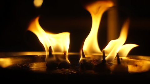 Macro shot of the sacred flames used in hindu puja ceremonies, cotton wicks dipped in ghee or clarified butter are set on fire for the puja or prayer ceremony. Placed on a bronze, brass plate the