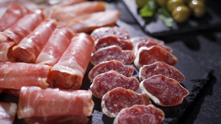 Restaurant meat platter (ham, salami, bacon) on the black stone tray Royalty-Free Stock Footage #1039908314