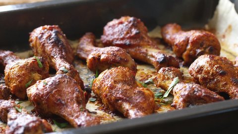 Roasted chicken legs BBQ in baking pan decorating with sesame and herbs. Video shot 4K 50 fps.