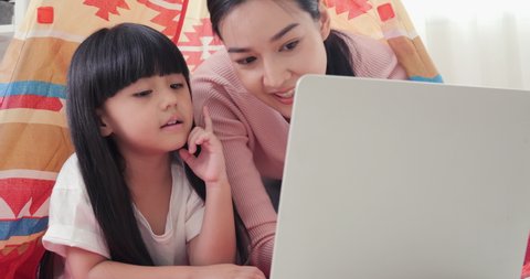 Mother and her daughter looking to laptop together at home. They using laptop with happy emotion. Lifestyle concept. Stockvideó