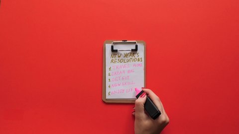 New Year's motivation, new beginnings, resolutions for the new year. Clipboard with plans check list on the red background.