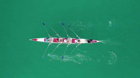 Aerial drone bird's eye view top down video of sport canoe operated by team of young women in emerald lake waters