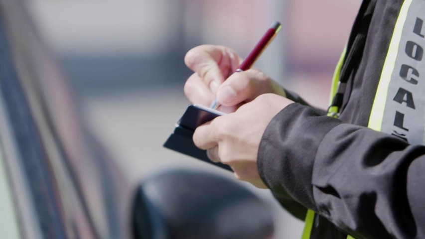 Close up of a police officer's hands writing a traffic ticket Royalty-Free Stock Footage #1039950296