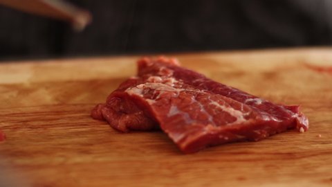 4k asian man hand slicing red raw beef steak, on wooden slice board, daylight, sharp small knife, black apron, chef prepare meat before cooking, steak, bbq, meat, gourmet, grocery  