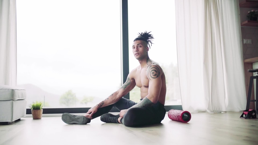 A mixed race young man resting after exercise indoors at home, a body workout.