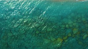 transparent bottom with beautiful stones Elli beach, Rhodes, Greece, view from above with drone on people bathing and surf with the waves.