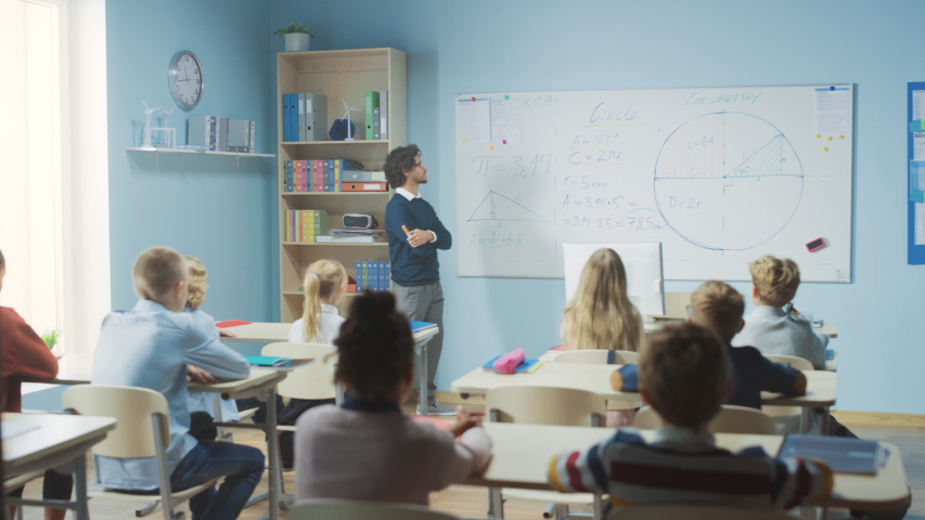 Talented Teacher Explains Lesson to a Classroom Full of Bright Diverse Children. In Elementary School with Group of Smart Multiethnic Learning Geometry and Physics, Boy Raising Hand with an Answer | Shutterstock HD Video #1039966982