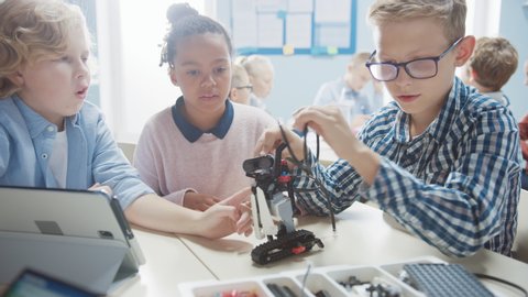 Elementary School Robotics Classroom: Diverse Group of Brilliant Children Building and Programming Robot Together, Talking and Working as a Team. Kids Learning Software Design and Robotics Engineering Stock Video
