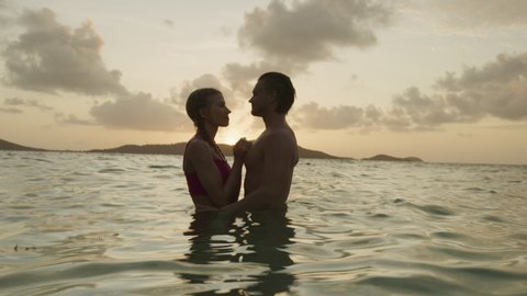 Romantic couple hugging and kissing in ocean at sunset / Jamesby Island, Tobago Cays, St. Vincent and the Grenadines
