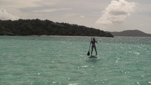 Couple paddleboarding in ocean near island / Tobago Cays, St. Vincent and the Grenadines