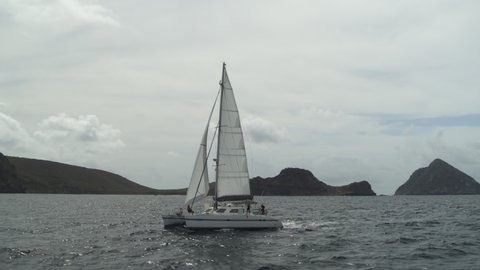 Panning shot of catamaran in ocean near island / Ronde Island, Grenada