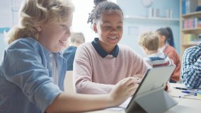 In the Elementary School: Girl and a Boy Work as a Team Using Tablet Computer. Diverse Classroom with Kids Learning Programming Language and Software Design - Powered by Shutterstock - Get 15% off with code: PIKWIZARD15
