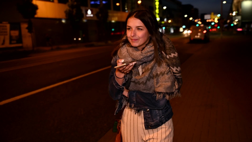 Happy young woman using smartphone at night