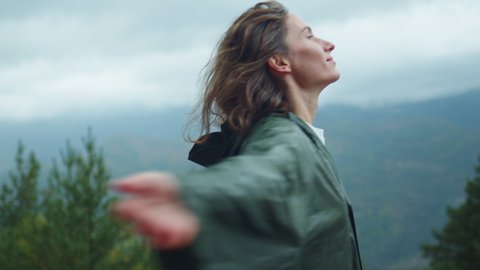 Female hiker with wet curly hair enjoying nature raising head up and looks in the sky feeling alive and free in nature breathing clean and fresh air at rainy day, Vacation Hiking in Pyrenees Mountains