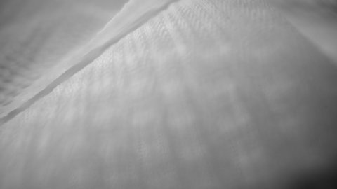 Shiny net cloth flowing texture dolly shot in close up view macro. Wavy clean silk weave material. Textile abstract background. Bed sheet, curtain and clothing industry concept.