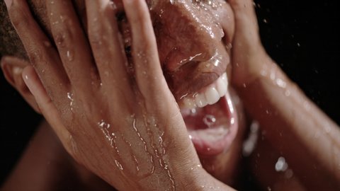 Beautiful black woman having a shower in slow motion. Head of a black woman under a shower on a black background