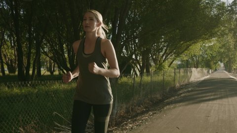 Slow motion tracking shot of runners passing in park and flirting / Saratoga Springs, Utah, United States