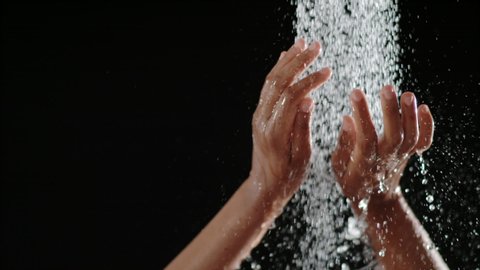 woman taking a shower in slow motion on a black background. beautiful woman having fun under a shower 