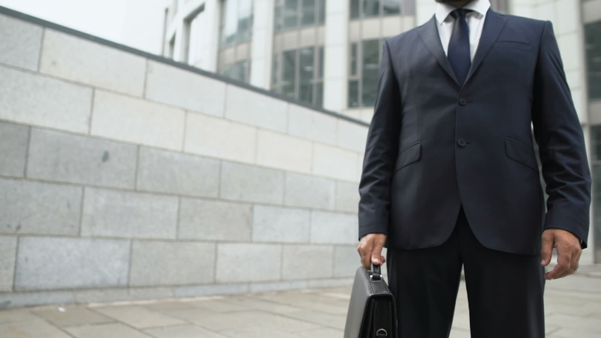 Successful man in suit adjusting tie, preparing for important business meeting