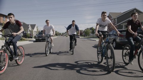 Tracking shot of boys riding bicycles on suburban street / Lehi, Utah, United States : vidéo de stock
