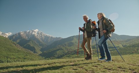 Mature caucasian couple on vacation, having a hike in spring mountains, spending time together after retirement together travelling - tourism, pension concept 4k