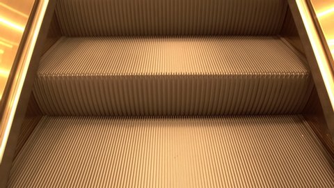 Golden escalator stairs close-up, moving in modern building. empty moving staircase