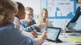 Elementary School Classroom: Enthusiastic Teacher Holding Tablet Computer Explains to a Brilliant Young Children How Wind Turbines Work. Kids Learning about Eco-Friendly Forms of Renewable Energy - Powered by Shutterstock - Get 15% off with code: PIKWIZARD15