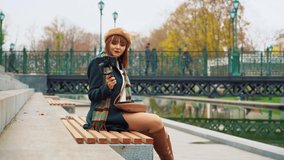 Elegant girl vlogger recording video in park using smartphone with steadicam