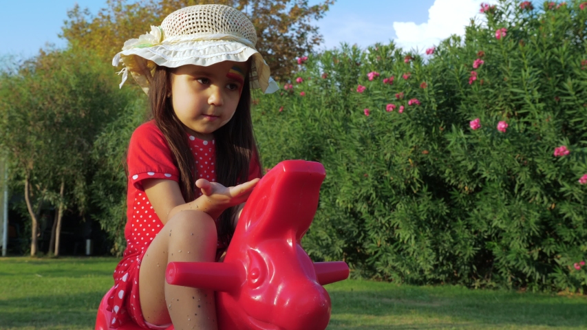 Little cute girl swinging on a swing at the playground in the summer.