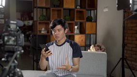 Asian young man blogger recording vlog talking to camera when work at home