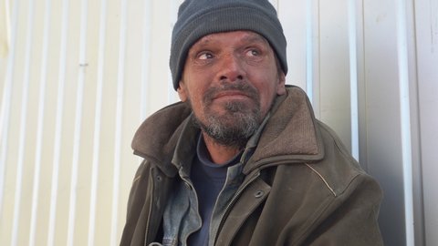Homeless man laughing through tears during a conversation on the street.