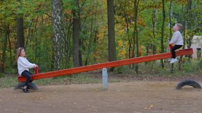 Brother and sister ride balancing swing in city park. Concept of good mood in children. Exercise releases endorphins, boosting mood and reducing stress of childhood. Siblings playing together outdoor. - Powered by Shutterstock - Get 15% off with code: PIKWIZARD15