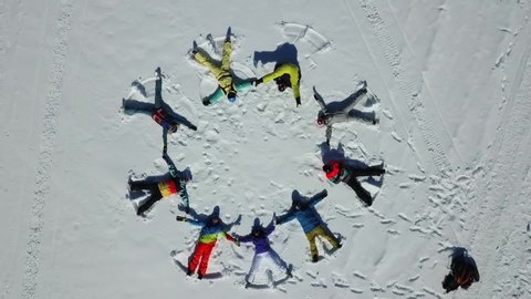 
Aerial top view on skiers making angels in the snow and lazing in the shape of a circle. People in colourful sport clothes. Andorra. 