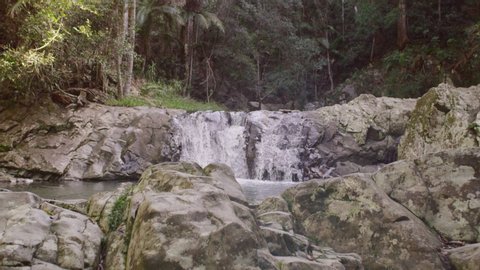 Beautiful lush forest and waterfalls in Australia moving past rocks and boulders. Wide shot on 4k RED camera.