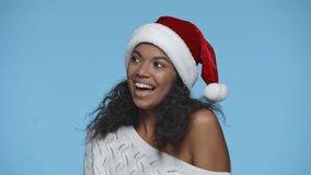 happy african american woman in Santa hat dancing isolated on blue