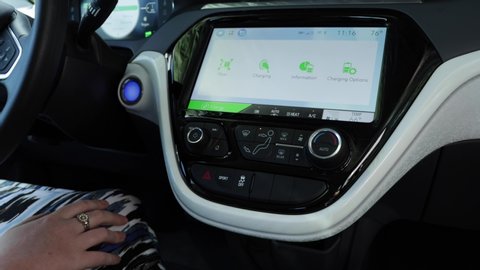 Dunedin, FL / US - 10 25 2019 : Female hand checking the charging status of her electric vehicle on her 2019 chevy bolt dashboard touch screen