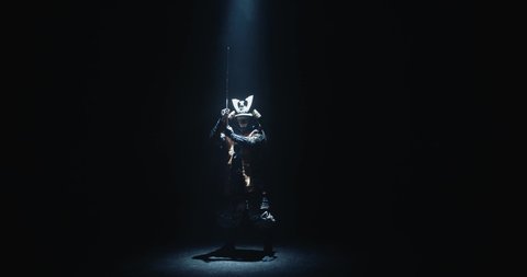 Asian man in traditional samurai costume stepping into the light with his sword prepared in hands, isolated on black background - culture, tradition concept 4k footage