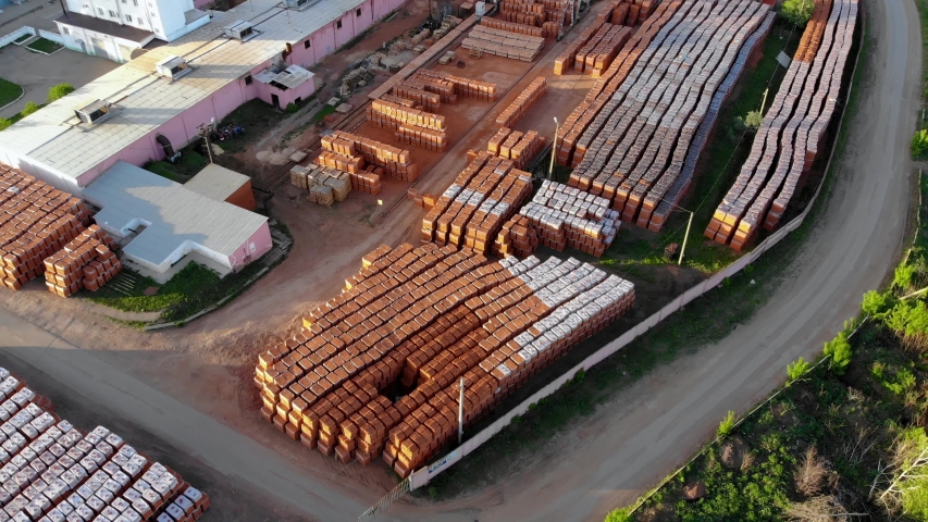 Aerial flying over the warehouse of a brick factory. Finished products are standing on the street and waiting for shipment. Taken by drone at sunset