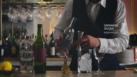 How to make a Martini Part 3 of 7: A bartender adds gin into his perfect martini in vintage bar. 4K RED with motion graphics.  