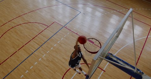 OVERHEAD HIGH ANGLE JIB SHOT African American black college male basketball player fails to dunk alone on the indoor court. 4K UHD 50 FPS SLOW MOTION RAW Graded footage