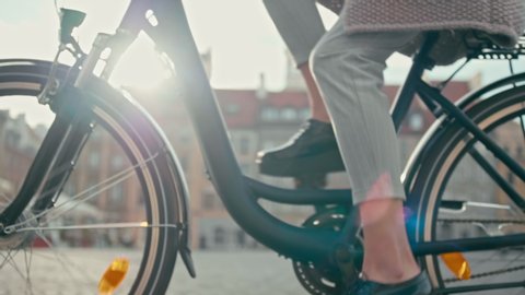 Close up of Bike Wheels and Female Feet in Patent Leather Shoes Cycling in Old Town Square in Autumn Sunny Day. Pretty Lady on Retro Bike. Urban Cycle Chic. 4K Tracking Low Angle Shot with Lens Flare