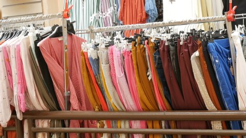 Various women's clothes hanging in a row on hangers in a clothing store