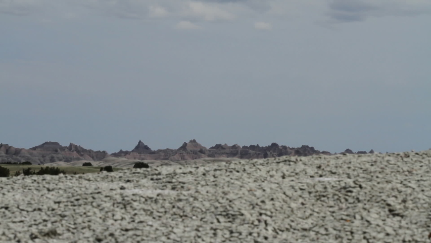 A hiker walks past camera, his legs and boots visible. Background is in foucs, foreground soft - Badlands National Park, South Dakota